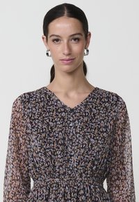 Vestido de manga larga y botón en tejido transparente con un estampado floral en tonos de rosa, púrpura y marrón; cuenta con un detalle de cintura fruncida.