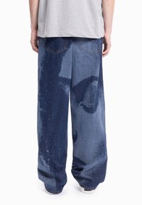 Spodnie dżinsowe o szerokich nogawkach z niebieskim gradientem i dwoma tylnymi kieszeniami. Materiał ma miękką fakturę i lekko sprany wygląd.