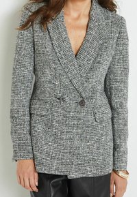 Blazer in tweed grigio e bianco con design doppiopetto, grandi bottoni, collo appuntito e tessuto testurizzato.