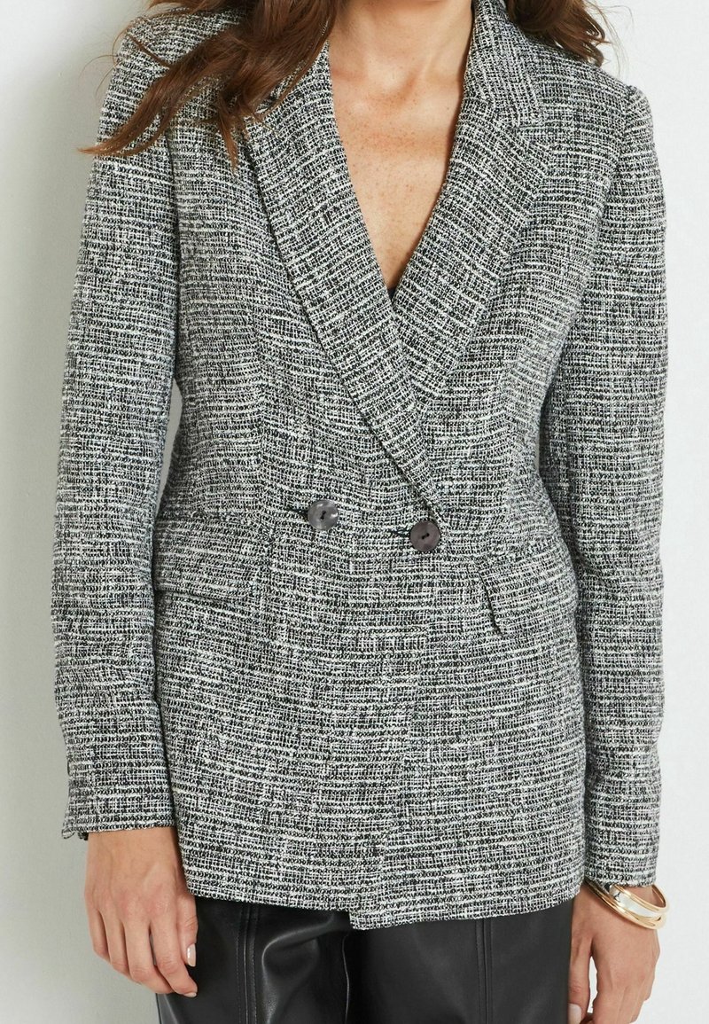 Blazer in tweed grigio e bianco con design doppiopetto, grandi bottoni, collo appuntito e tessuto testurizzato.
