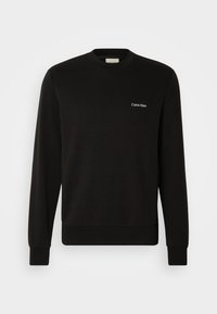 Sweatshirt noir à manches longues et col rond avec petit logo blanc "Calvin Klein" sur le côté gauche de la poitrine sur fond uni.