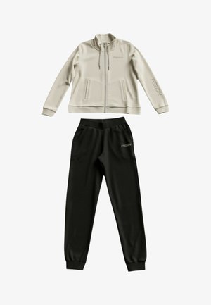 Giacca beige con zip, coulisse e due tasche laterali, abbinata a pantaloni jogger neri con polsini elasticizzati, entrambi con il marchio "FREDDY".