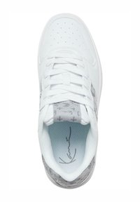 Balts sporta apavu pāris ar perforētu purngalu, pelēka rakstaina mēle un papēdis, baltas šņores un mīkstināta apkakle, skatīts no augšas.