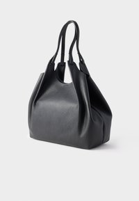 Fekete bőr bevásárlótáska mintás felszínnel, két masszív fogantyúval és tágas, puha test kialakítással, nagy kapacitással.