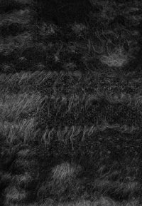 Las fibras texturizadas en negro y gris crean una apariencia estratificada, con tonos y longitudes variables que brindan una superficie suave y difusa.