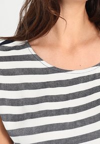 Top a rayas con escote redondo, que presenta franjas horizontales gruesas alternas en gris y blanco, hecho de una tela texturizada.