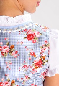 Robe à motif floral avec une base en vichy bleu, manches blanches à volants et détails brodés le long de l'encolure et des coutures.