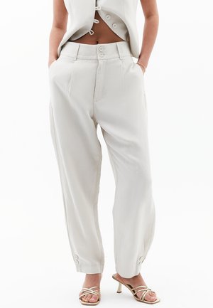 Lichtbeige wijde broek van zachte stof, met een hoge taille, zakken aan de voorkant en knoopaccenten bij de manchetten.