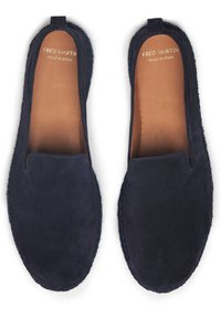 Zapatos de ante azul marino tipo mocasín con una textura suave, punta redondeada y bordes cosidos. El interior cuenta con un forro de cuero en tono marrón claro con la marca.