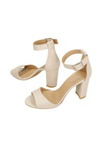 Béžové kožené sandály na vysokém podpatku s otevřenou špičkou, páskem kolem kotníku a blokovým podpatkem. Hladký povrch a minimalistický tvar.