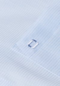 Helles blaues, strukturiertes Gewebe mit einem kleinen, gestickten Akzent. Verfügt über ein geometrisches Muster und ein minimalistisches Design.