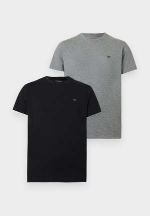 Deux t-shirts unis à col rond, un noir et un gris, chacun avec un petit logo discret sur la poitrine, côté gauche.