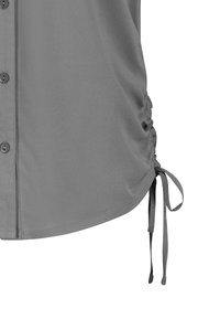 Gray blouse featuring a button front, soft fabric, gathered side with ties, and a curved hem.