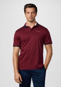 Burgundské polokošele vyrobené z ľahkého materiálu, s kontrastným námorníckym golierom so červenými a bielymi pruhmi, a logom na hrudi.