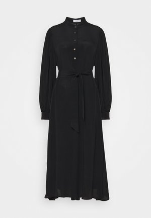 Robe midi noire à manches longues avec col haut, devant boutonné, poignets froncés et ceinture à nouer à la taille sur fond uni.