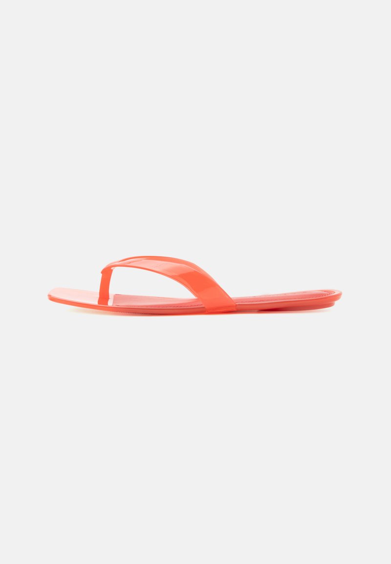 Sandale plate orange à enfiler avec une bride simple entre les orteils, semelle lisse et finition brillante, présentée sur fond blanc.