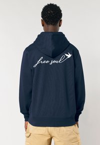 Felpa navy realizzata in tessuto morbido, con una stampa bianca in corsivo "free soul" e un piccolo design di un uccello sulla schiena. Vestibilità regular.
