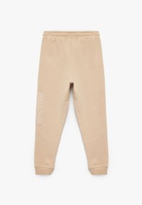 Beige Jogginghose aus weichem Stoff, mit elastischem Bund, gerippten Bündchen und einer strukturierten seitlichen Taschenbeschreibung.