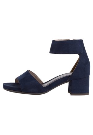 Laivansiniset mokkanahka korkokengät, joissa on nilkkaremmi, avonainen varvasosa ja lohkokorko. Tasainen pinta ja pehmustettu pohjallinen.