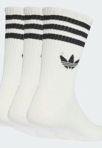 Drei Paar weißer Baumwollsocken mit gerippter Struktur, die oben schwarze Streifen und ein schwarzes Logo mit drei Blättern an der Seite haben.