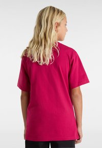 Magenta puuvillapaita lyhyillä hihoilla, rento leikkaus ja yksinkertainen muotoilu. Takaa näkyy sileä rakenne ja vähäiset yksityiskohdat.