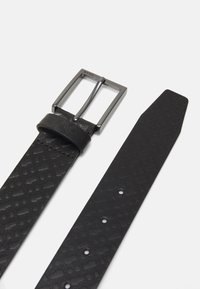 Zwarte leren riem met een gestructureerd ontwerp, voorzien van een zilverkleurige metalen gesp en een soepele band met meerdere verstelgaten.