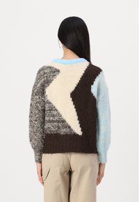 Sweter dzianinowy z kontrastowymi wzorami geometrycznymi w odcieniach brązu, kremu i jasnoniebieskiego, z okrągłym dekoltem i teksturowanymi rękawami.