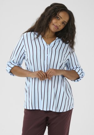 Blusa a righe azzurro chiaro con righe marroni verticali, abbottonatura e maniche arrotolate. Tessuto morbido con una vestibilità rilassata.