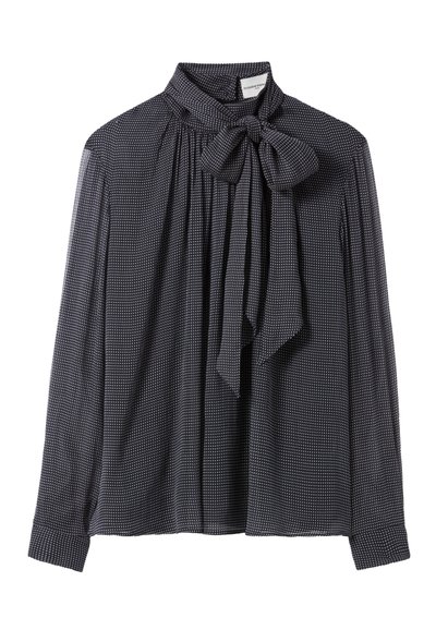 Blusa negra de manga larga con lunares blancos, cuello alto y un gran lazo atado en el escote.