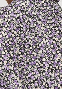 Tessuto floreale con piccoli fiori viola e margherite bianche su sfondo nero, con una finitura testurizzata e una leggera lucentezza.
