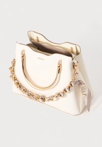 Bolso estructurado blanco con un asa de cadena en tono dorado, material texturizado y un pañuelo con patrón sujeto al lado.