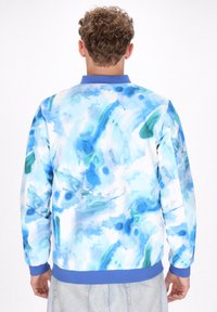 Kleurrijke sweatshirt met een lichtblauw aquarelpatroon, voorzien van een blauwe kraag en mouwen, gemaakt van een gladde, zachte stof.