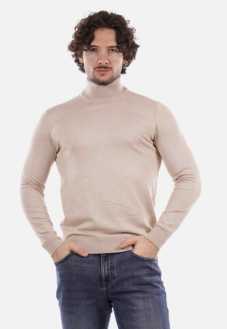 Maglione beige a collo alto realizzato in morbido tessuto a maglia, con maniche lunghe e design aderente, abbinato a jeans blu scuro.