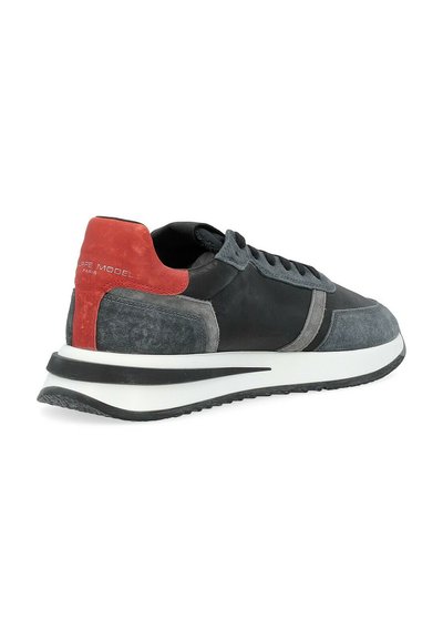 Sneaker con una toma superiore in pelle nera, accenti in suede grigio, un tab per il tallone rosso e una suola bianca con un logo sul retro.