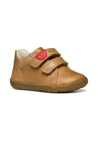 Scarpe per bambini in pelle marrone con due cinturini in Velcro, un accento rosso vicino alla parte superiore, punta arrotondata e suola in gomma con battistrada testurizzato.