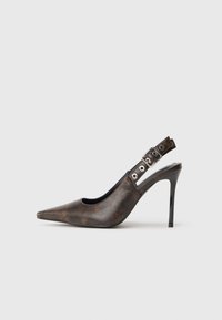 Pantofii cu toc înalt din piele maro, cu vârful ascuțit și curea reglabile pe călcâi, având toc stiletto negru, pe un fundal simplu.