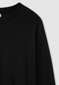 Felpa nera con scollo rotondo a coste, texture morbida e maniche lunghe. Il design presenta una vestibilità comoda e dettagli minimi.