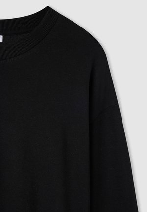 Czarna bluza z okrągłym dekoltem, o prążkowanej fakturze, miękka w dotyku, z długimi rękawami. Projekt cechuje się luźnym krojem i minimalnym wykończeniem.