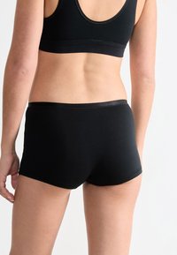 Svarta bomullsshorts med en mjuk textur, elastisk midja och en kroppsnära passform, designade för komfort och en säker passform.