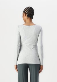 Langermet, lys grå T-skjorte med rund hals, slim fit og myk tekstur. Kombinert med mørkegrønne, løstsittende bukser.