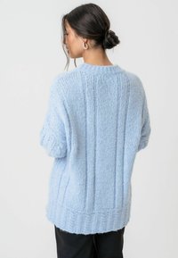 Ljusblå stickad tröja med texturerade vertikala ränder, nedhoppade axlar och ribbat avslut. Mysigt, mjukt material med en avslappnad passform.