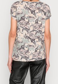 Kortærmet bluse med paisley- og blomstermønster i dæmpede farver som pink, grøn og brun, lavet af let materiale.