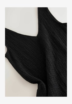 Must have mustrametega musta värvi lipsudeta top, mis on laotatud heleda tausta peale, näidates kangast üksikasju ja ümarat kaelust.