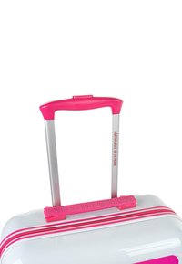 Maleta rígida con un cuerpo blanco, cremallera rosa y un asa rosa con un tirador plateado. Texto de marca destacado en el asa.