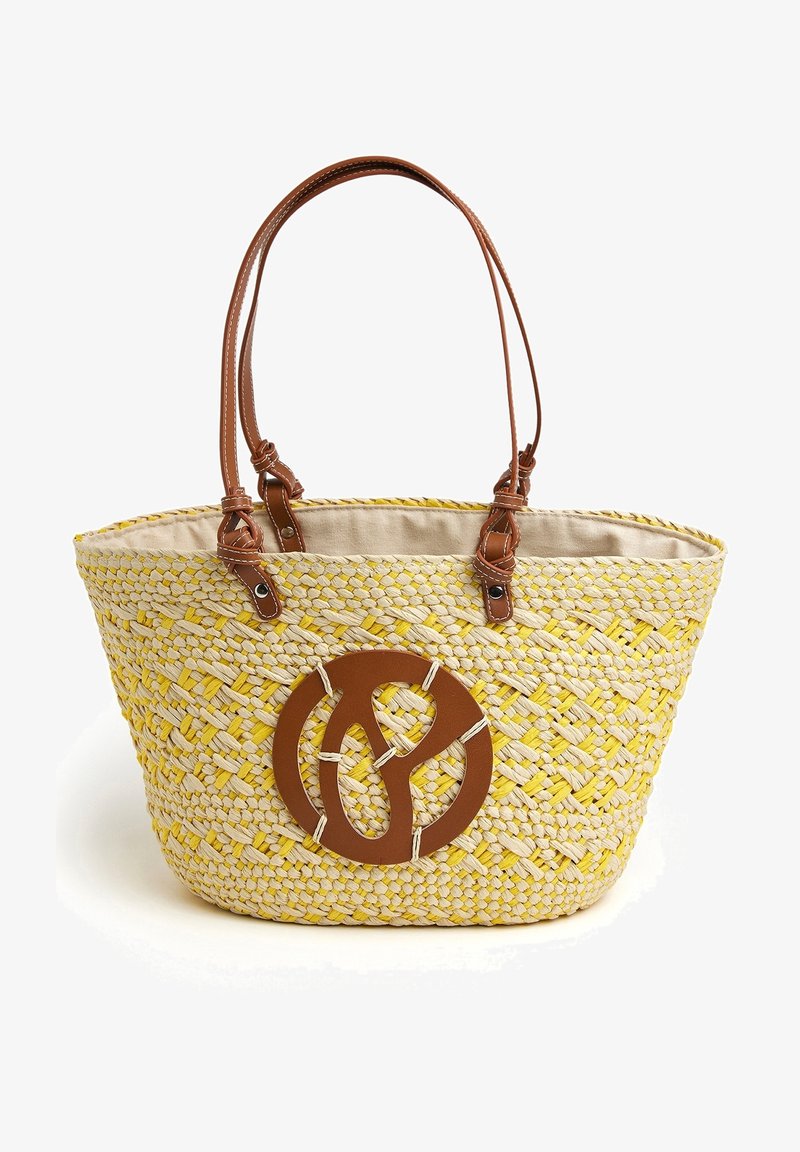 Sac cabas en paille tissée avec des touches jaunes, poignées en cuir beige et un patch décoratif rond en cuir beige sur le devant.