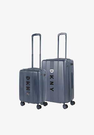 Dos maletas rígidas de color azul metálico con asas extensibles y cuatro ruedas giratorias, con la marca DKNY en negro en la parte frontal.
