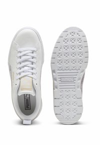 Balts Puma sporta apavu pāris ar auklām, redzams no augšas un apakšas, ar teksturētu saķeres rakstu un Puma logotipu uz zolītes un mēlītes.