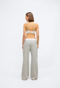 Grå bomull lounge-sett med sports-bh med justerbare stropper og bukser med vide ben og elastisk midje, minimalistisk design.