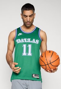 Πράσινη φανέλα μπάσκετ με τη λέξη «DALLAS» σε λευκό, αριθμός «11» από κάτω, μπλε περιθώριο, ύφασμα από δίχτυ, συνοδευόμενη από πορτοκαλί μπάλα μπάσκετ.