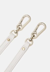 Deux lanières en cuir blanc avec des rivets dorés, chacune fixée à un fermoir métallique argenté brillant avec un crochet à ressort.